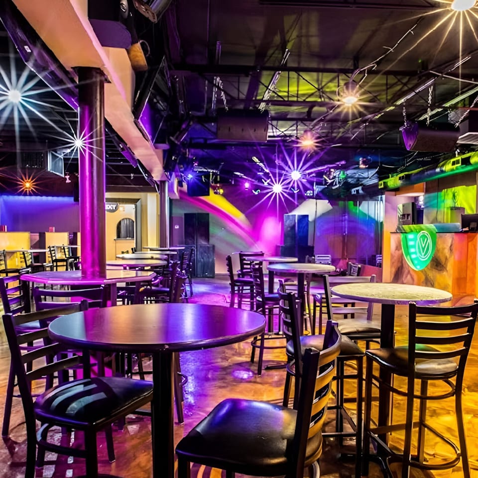 Views Bar & Grill interior with tables, chairs, and vibrant purple and yellow lighting.