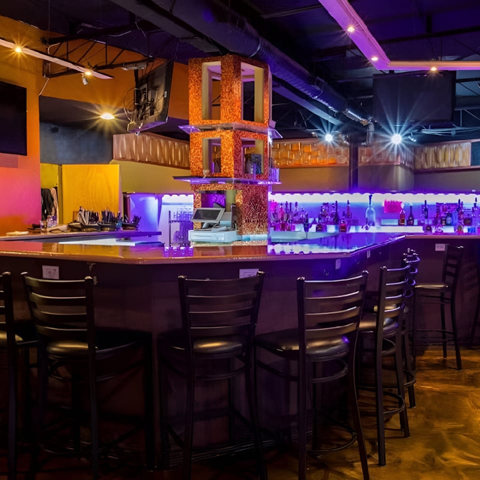 Views Bar & Grill interior with a long bar, stools, and purple neon lighting.