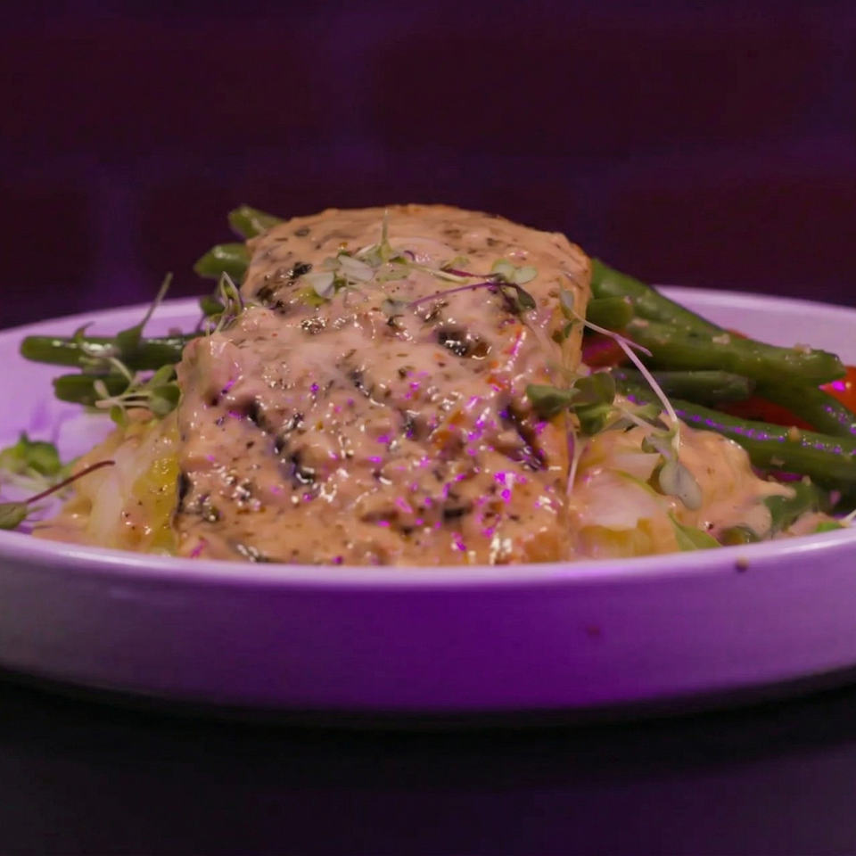 Creamy chicken dish with green beans and mashed potatoes, garnished with microgreens.